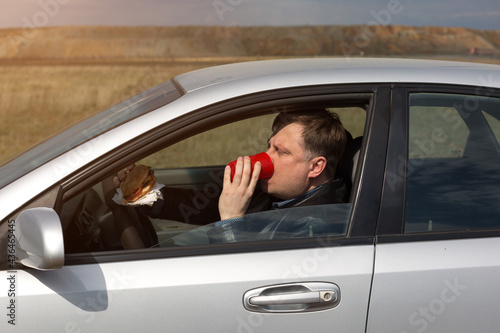 The manager eats lunch at the wheel in the car. © ALEXEY