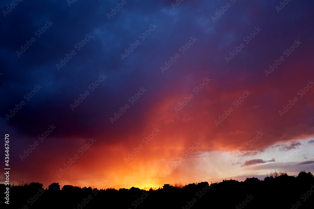 Beautiful fiery red sunset. Evening landscape. Village and forest fire silhouette. Cloudy weather. Scenic cloudscape. Dramatic sky. Copy space. Wallpaper. Storm wind. Summer thunderstorm