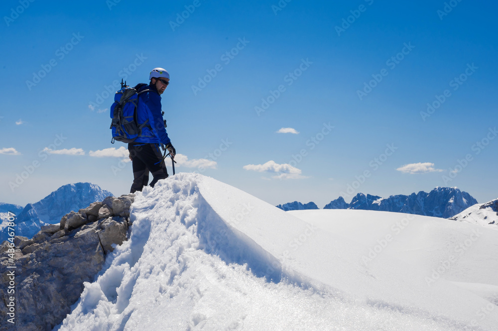 climber on the top of the alpine mountain Mala Mojstrovka against the backdrop of snowy alps