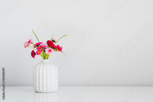 Fresh summer bouquet of pink flowers in vase on white background. Floral home decor. Minimal style.