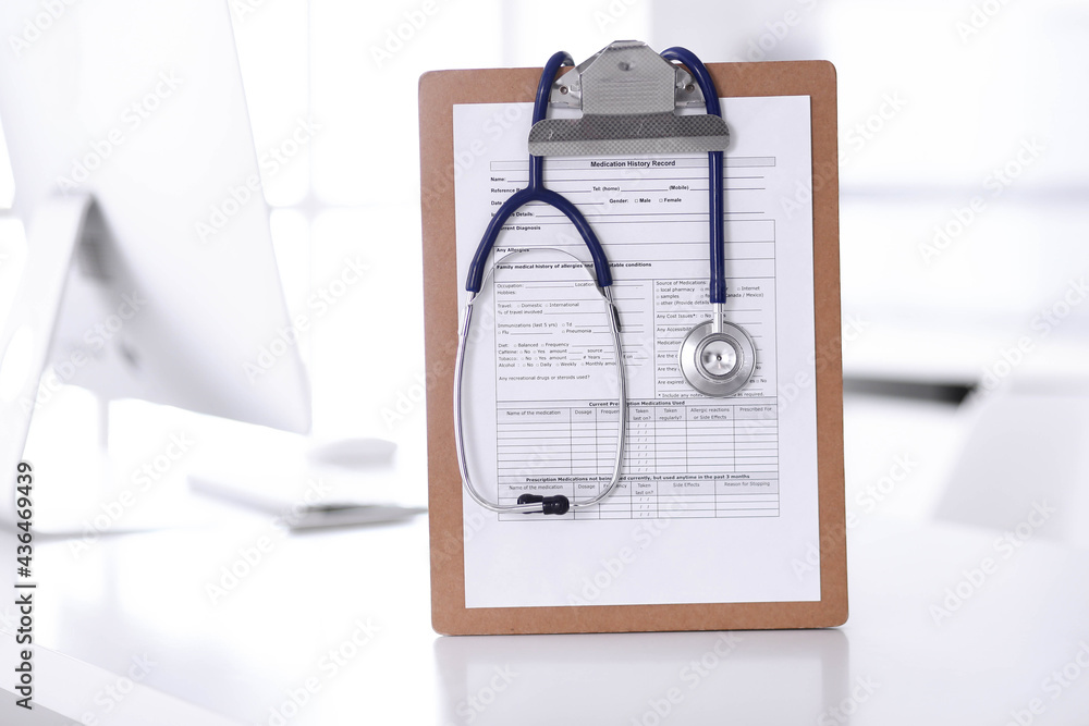 Stethoscope and clipboard with medication history records are on the table at the doctor's working place. Medicine and health care concept Stethoscope and clipboard with medication history records are on the table at the doctor's working place. Medicine and health care concept