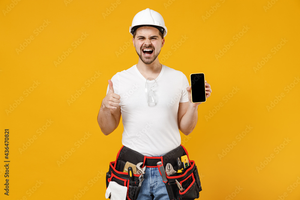 Young employee handyman man in protective helmet hardhat use mobile phone blank screen workspace thumb up isolated on yellow background Instruments accessories renovation apartment room Repair concept Young employee handyman man in protective helmet hardhat use mobile phone blank screen workspace thumb up isolated on yellow background Instruments accessories renovation apartment room Repair concept
