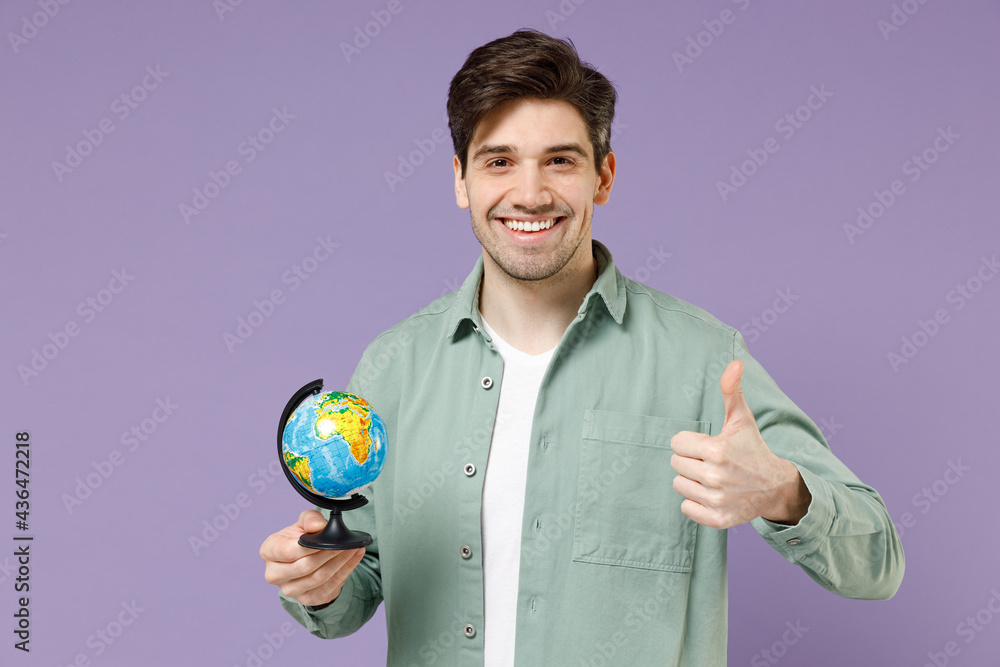 Young fun happy caucasian man 20s in casual mint shirt white t-shirt spin touch Earth world globe show thumb up gesture isolated on purple violet background studio portrait People lifestyle concept Young fun happy caucasian man 20s in casual mint shirt white t-shirt spin touch Earth world globe show thumb up gesture isolated on purple violet background studio portrait People lifestyle concept