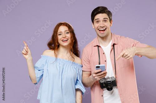 Two traveler tourist woman man couple in casual clothes use mobile phone point finger aside workspace isolated on purple background Passenger travel abroad weekend getaway Air flight journey concept.