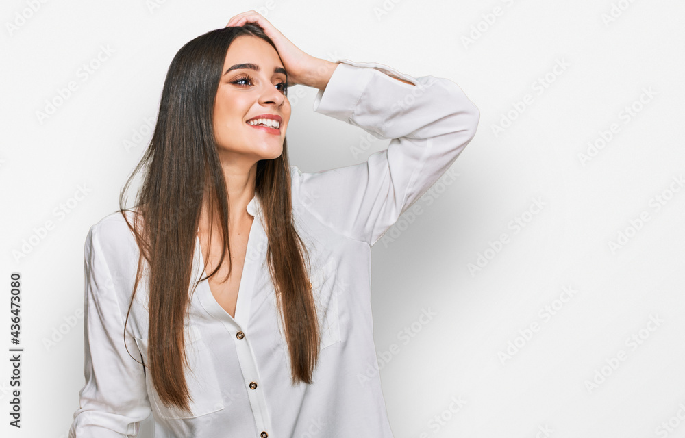 Young beautiful woman wearing casual white shirt smiling confident touching hair with hand up gesture, posing attractive and fashionable Young beautiful woman wearing casual white shirt smiling confident touching hair with hand up gesture, posing attractive and fashionable