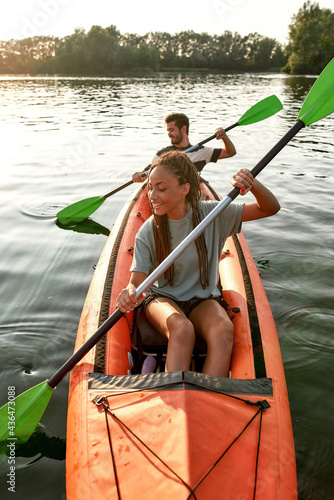 Картината върху платно Adventurous young girlfriend paddling kayak on a river together with her boyfrie