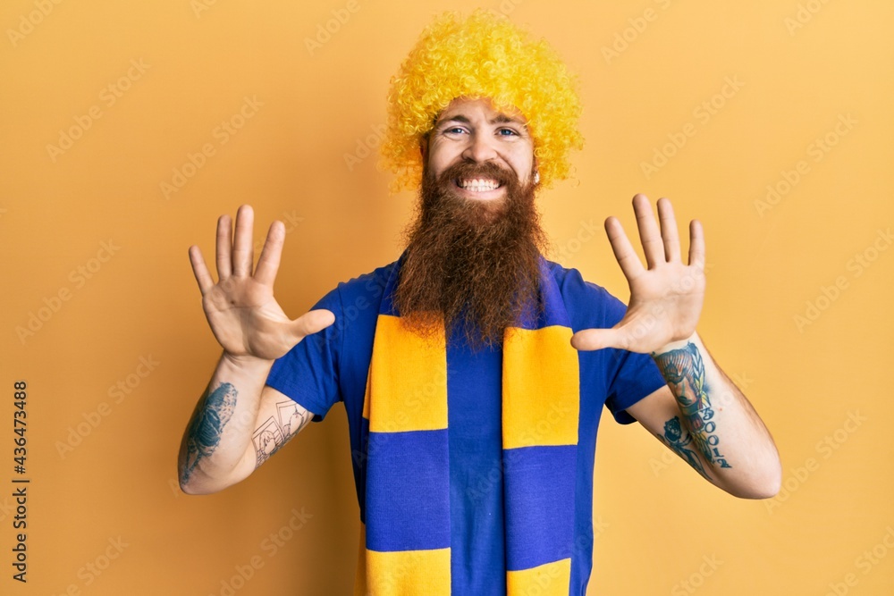 Redhead man with long beard football hooligan cheering game wearing funny wig showing and pointing up with fingers number ten while smiling confident and happy. Redhead man with long beard football hooligan cheering game wearing funny wig showing and pointing up with fingers number ten while smiling confident and happy.