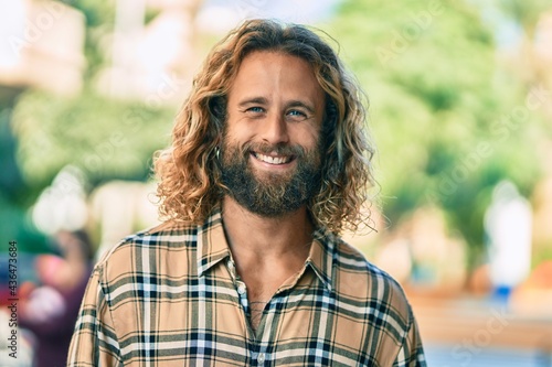 Young caucasian man with long hair smiling happy at the park.