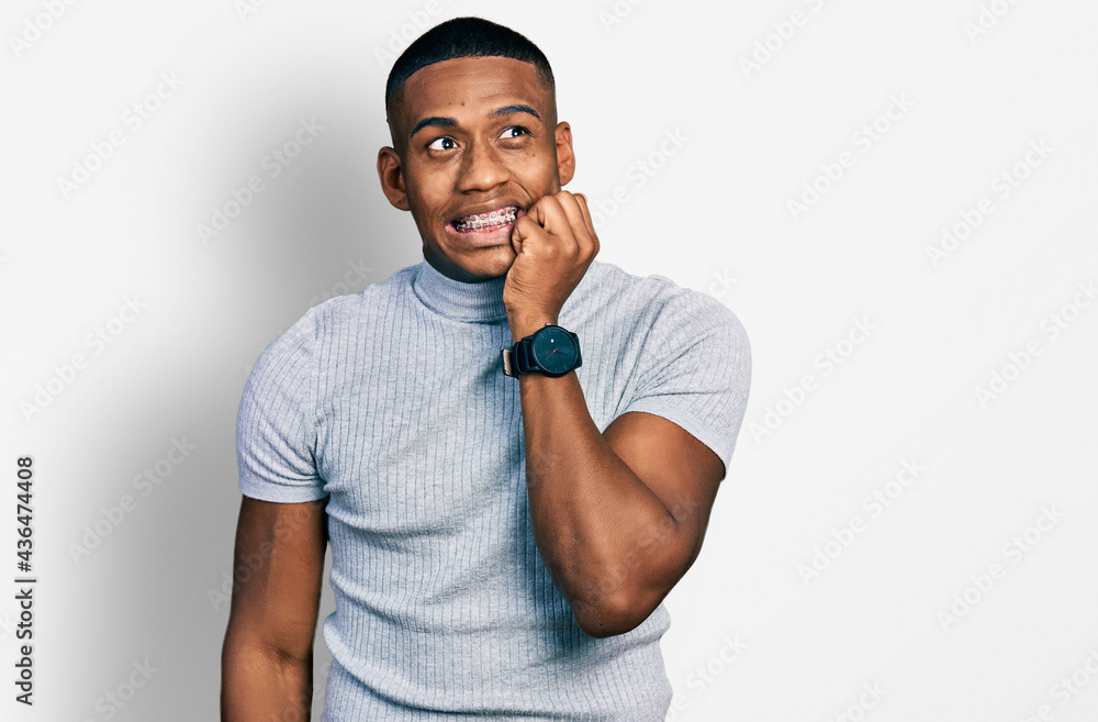 Young black man wearing casual t shirt looking stressed and nervous with hands on mouth biting nails. anxiety problem. Young black man wearing casual t shirt looking stressed and nervous with hands on mouth biting nails. anxiety problem.