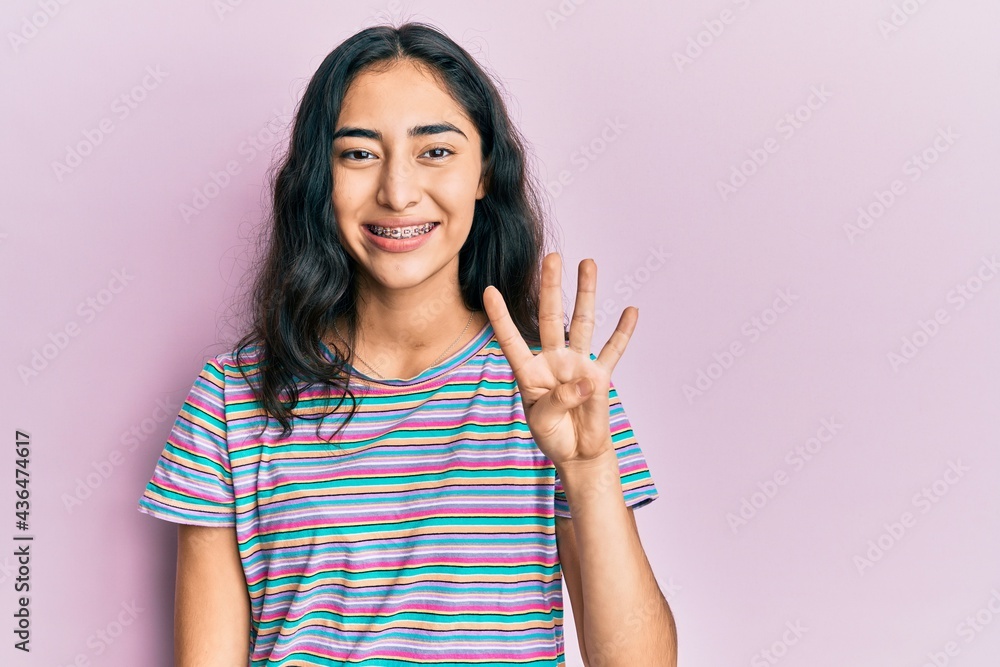 Hispanic teenager girl with dental braces wearing casual clothes showing and pointing up with fingers number four while smiling confident and happy. Hispanic teenager girl with dental braces wearing casual clothes showing and pointing up with fingers number four while smiling confident and happy.