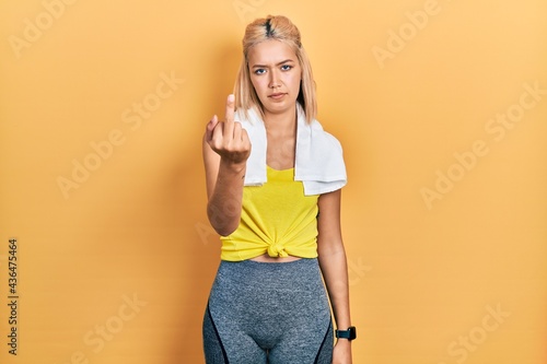 Beautiful blonde sports woman wearing workout outfit showing middle finger, impolite and rude fuck off expression © Krakenimages.com