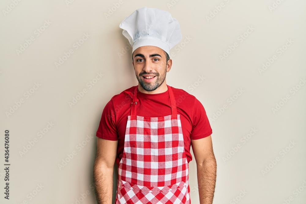 Young hispanic man wearing baker uniform with a happy and cool smile on face. lucky person. Young hispanic man wearing baker uniform with a happy and cool smile on face. lucky person.