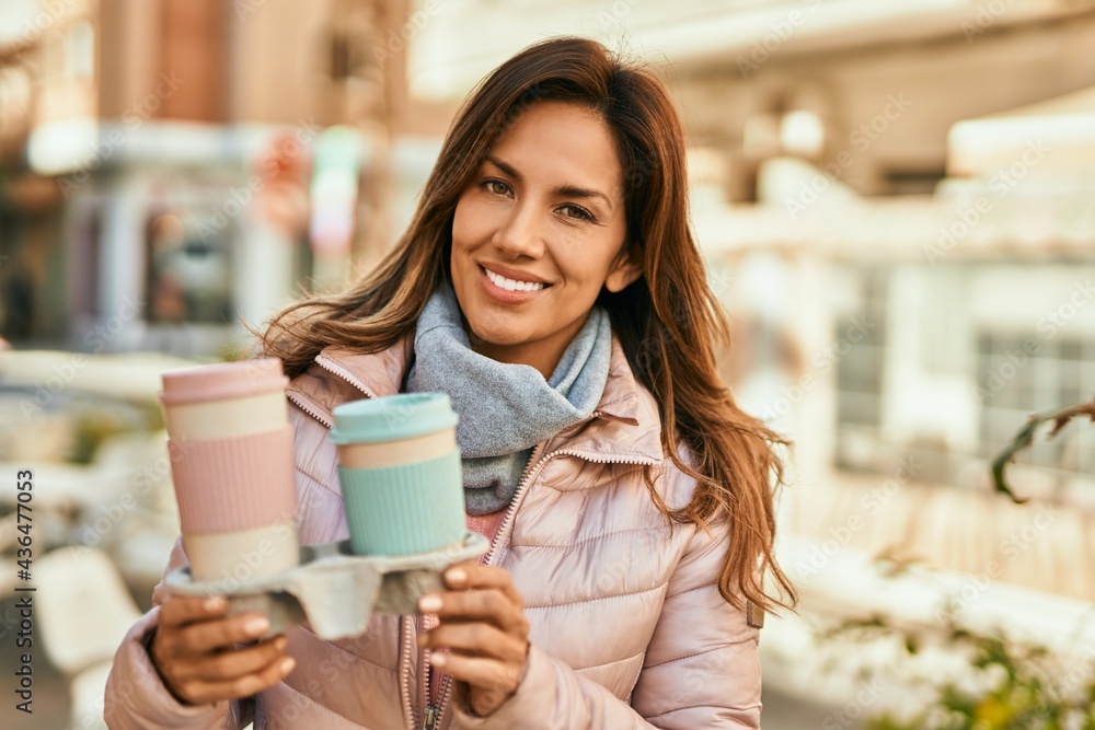 Young hispanic woman smiling happy holding take away coffee at the city. Young hispanic woman smiling happy holding take away coffee at the city.