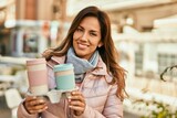 Young hispanic woman smiling happy holding take away coffee at the city.
