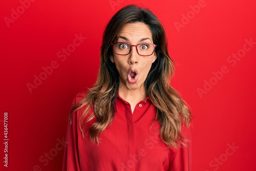Young latin woman wearing casual clothes and glasses afraid and shocked with surprise expression, fear and excited face.