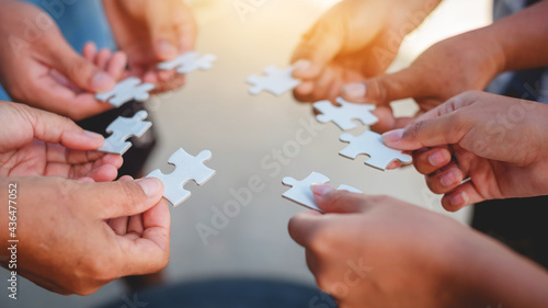 Hands of diverse people assembling jigsaw puzzle, team put pieces together searching for right match, help support in teamwork to find common solution concept, top close up view