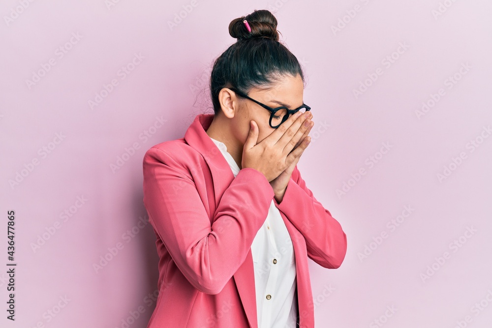 Beautiful middle eastern woman wearing business jacket and glasses with sad expression covering face with hands while crying. depression concept.