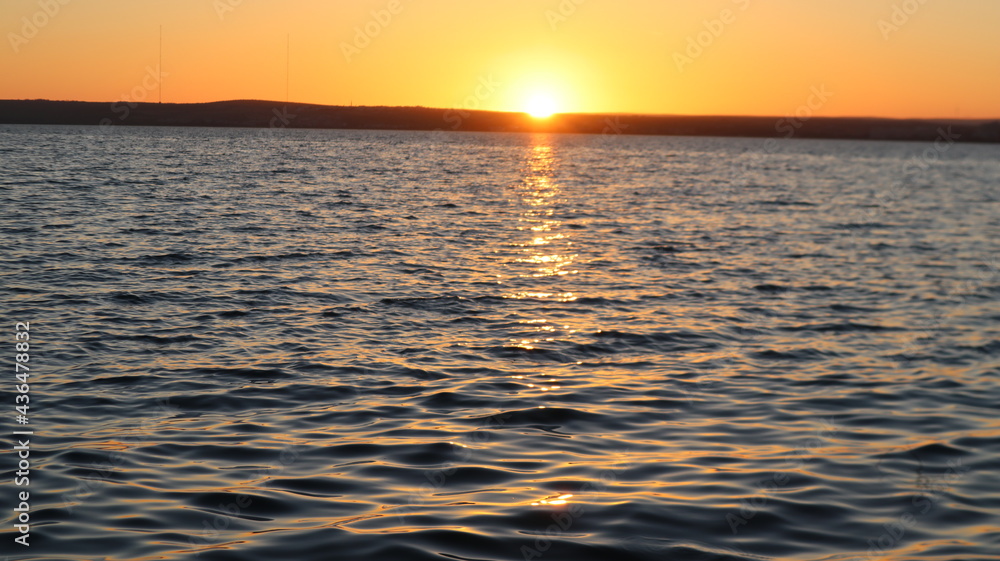 Obraz premium Orange gold sunset on sea surface. Sun reflection on water. Landscape under colorful sky at sunset. Orange sundown reflecting from calm Aegean sea at golden hours.