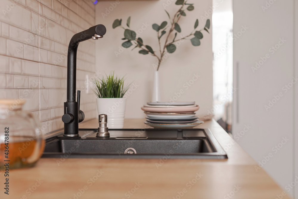 Black kitchen sink made of artificial stone in a wooden home interior. Black kitchen sink made of artificial stone in a wooden home interior.