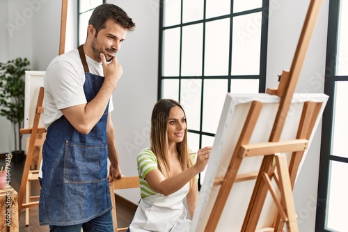 Student and teacher smiling happy painting at art studio.