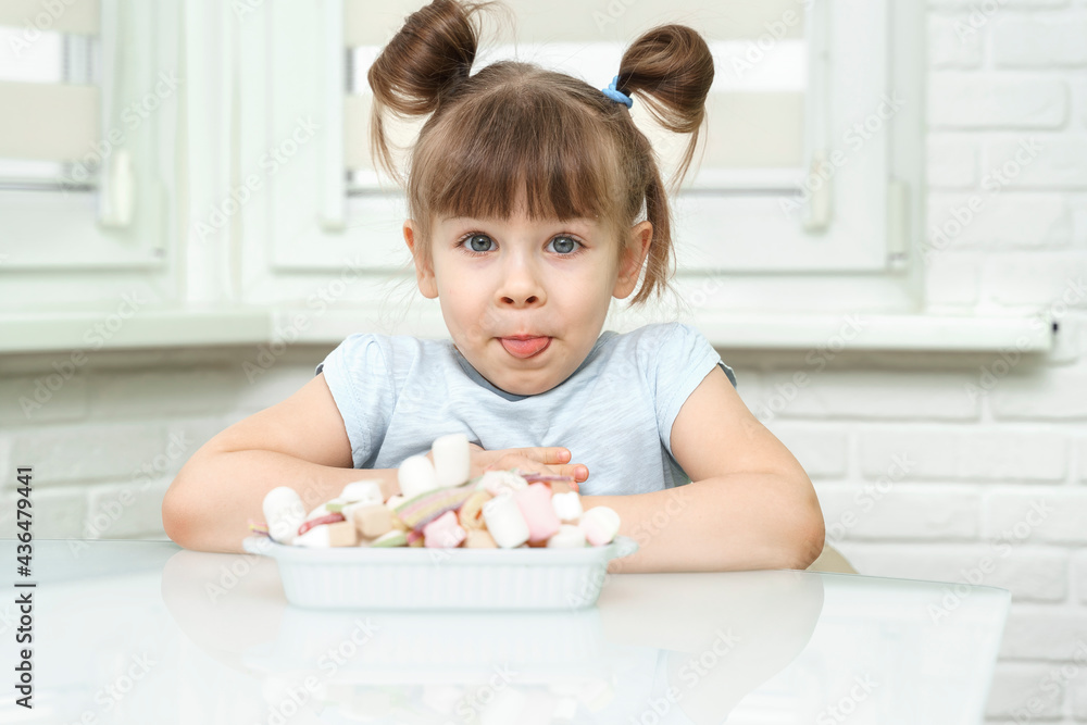 happy contented little girl eating marshmallows from a plate full of sweets. the child is addicted to sugar happy contented little girl eating marshmallows from a plate full of sweets. the child is addicted to sugar
