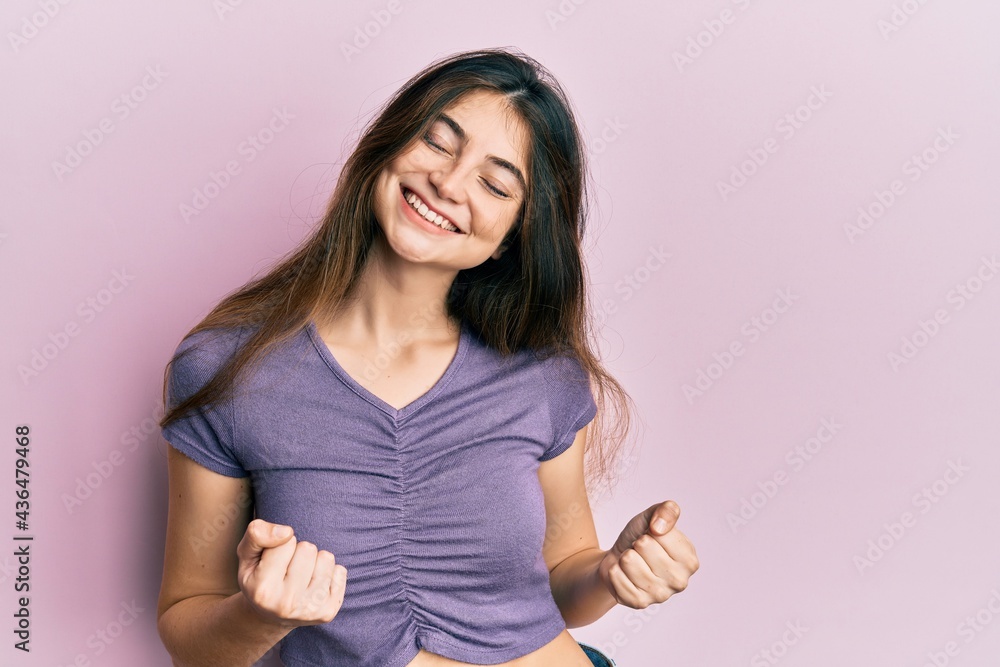 Fototapeta premium Young caucasian woman wearing casual clothes very happy and excited doing winner gesture with arms raised, smiling and screaming for success. celebration concept.