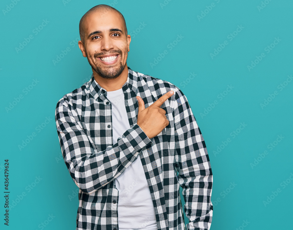 Hispanic adult man wearing casual clothes cheerful with a smile of face pointing with hand and finger up to the side with happy and natural expression on face Hispanic adult man wearing casual clothes cheerful with a smile of face pointing with hand and finger up to the side with happy and natural expression on face