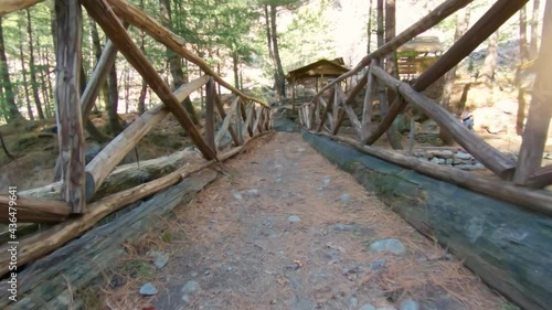 Point of View shot of a man walking on the wooden bridge above the river stream in the forest at Soyal village near Manali in Himchal Pradesh, India photo