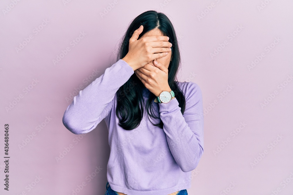 Young hispanic woman wearing casual clothes covering eyes and mouth with hands, surprised and shocked. hiding emotion Young hispanic woman wearing casual clothes covering eyes and mouth with hands, surprised and shocked. hiding emotion