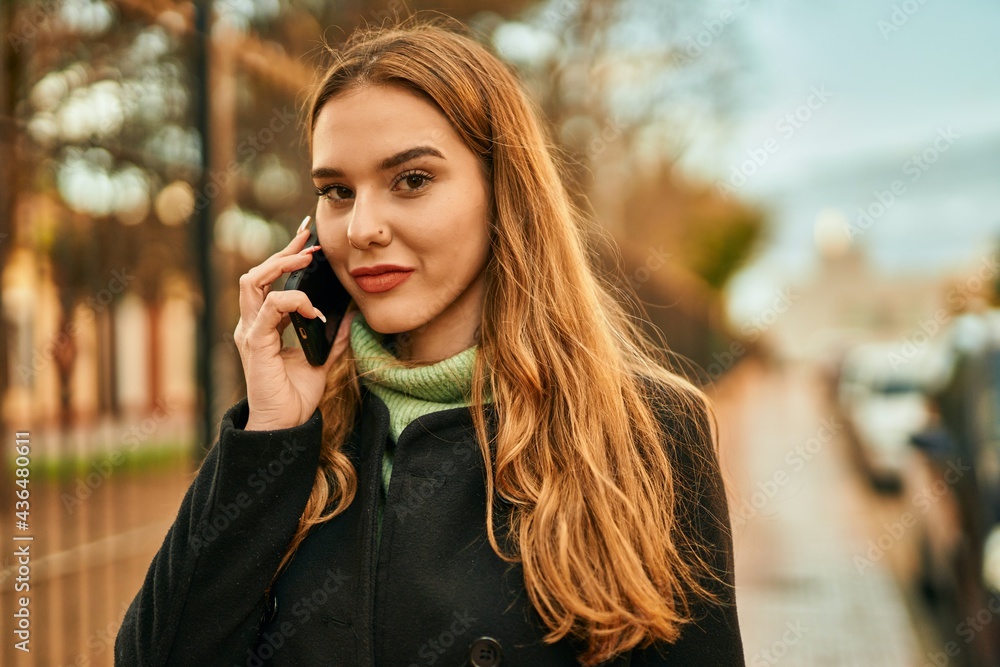 Young blonde girl smiling happy talking on the smartphone at the city. Young blonde girl smiling happy talking on the smartphone at the city.