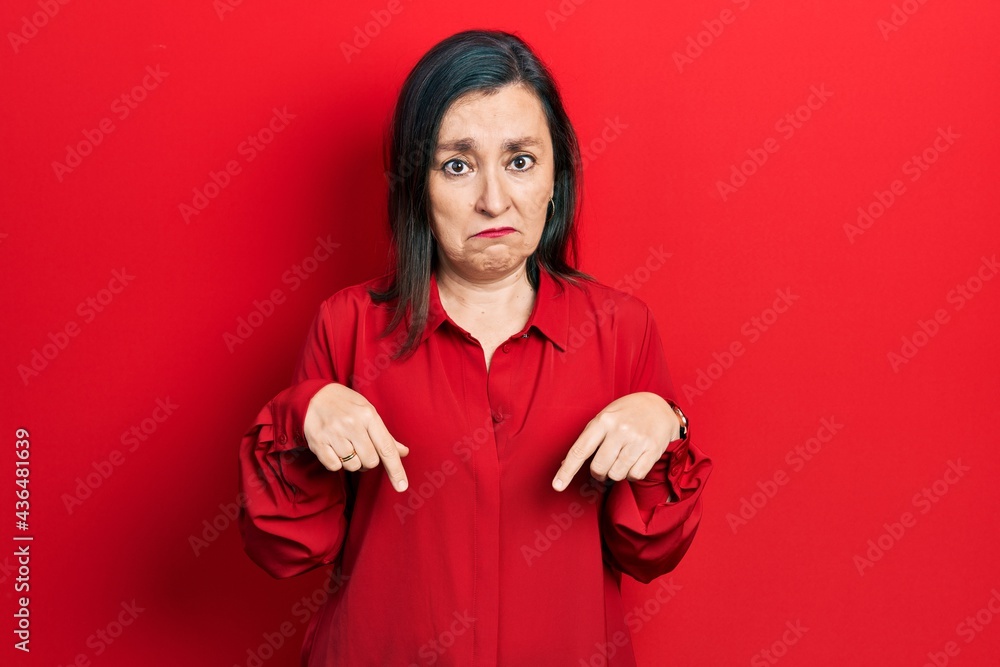 Middle age hispanic woman wearing casual clothes pointing down looking sad and upset, indicating direction with fingers, unhappy and depressed. Middle age hispanic woman wearing casual clothes pointing down looking sad and upset, indicating direction with fingers, unhappy and depressed.