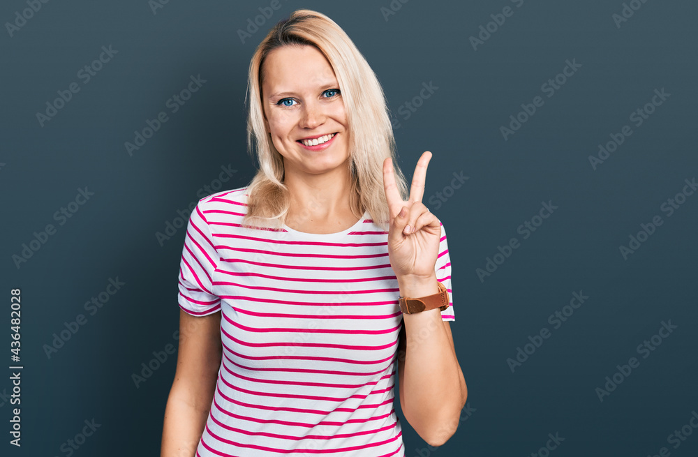 Young caucasian woman wearing casual clothes showing and pointing up with fingers number two while smiling confident and happy. Young caucasian woman wearing casual clothes showing and pointing up with fingers number two while smiling confident and happy.