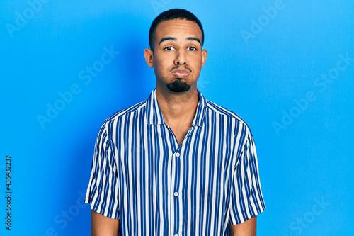 Young african american man wearing casual clothes puffing cheeks with funny face. mouth inflated with air, crazy expression.