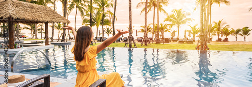 Young woman traveler relaxing and enjoying the sunset by a tropical resort pool while traveling for summer vacation, Banner panorama
