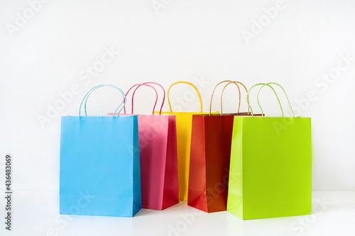 Colorful paper shopping bags on white table and background with copy space