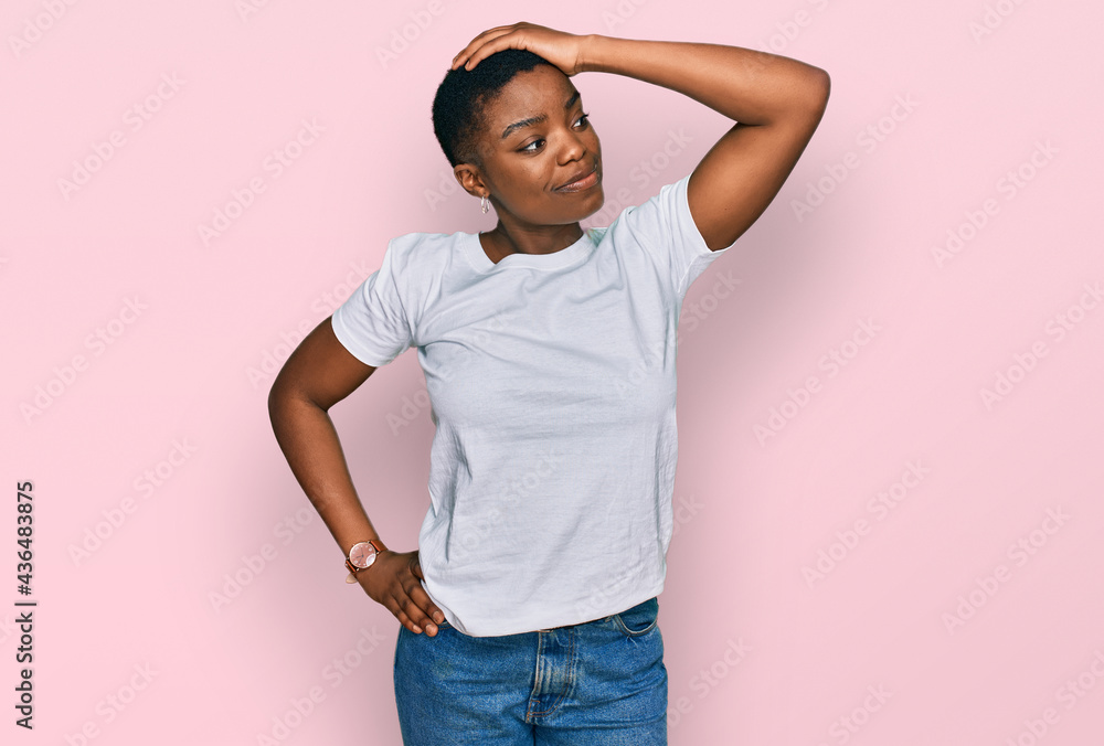Young african american woman wearing casual white t shirt smiling confident touching hair with hand up gesture, posing attractive and fashionable Young african american woman wearing casual white t shirt smiling confident touching hair with hand up gesture, posing attractive and fashionable