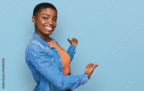 Young african american woman wearing casual clothes inviting to enter smiling natural with open hand