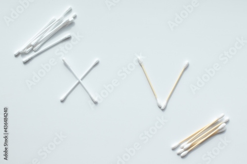 Ecological concept. Check mark made from wooden cotton swabs and cross made of plastic cotton swabs. Zero waste concept