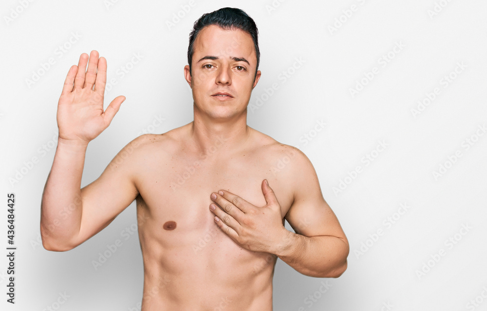 Fototapeta premium Handsome young man wearing swimwear shirtless swearing with hand on chest and open palm, making a loyalty promise oath