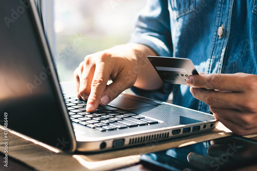 Businessman hand holding credit card with using laptop for online shopping while making orders at home. business, lifestyle, technology, ecommerce, digital banking and online payment concept.