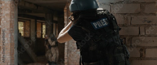 Valokuva CU Portrait of Caucasian female war journalist wearing protective helmet and bulletproof vest gear taking photos under fire