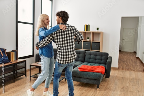 Young couple smiling happy dancing at home.