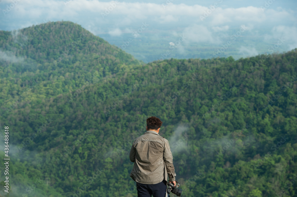Naklejka premium Man photographer taking photographs with digital camera in a mountains. Creative professional photographing. Travel, hobby and active lifestyle concept