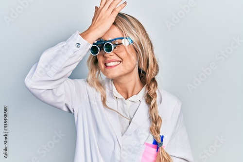Beautiful young blonde woman wearing optometry glasses surprised with hand on head for mistake, remember error. forgot, bad memory concept.