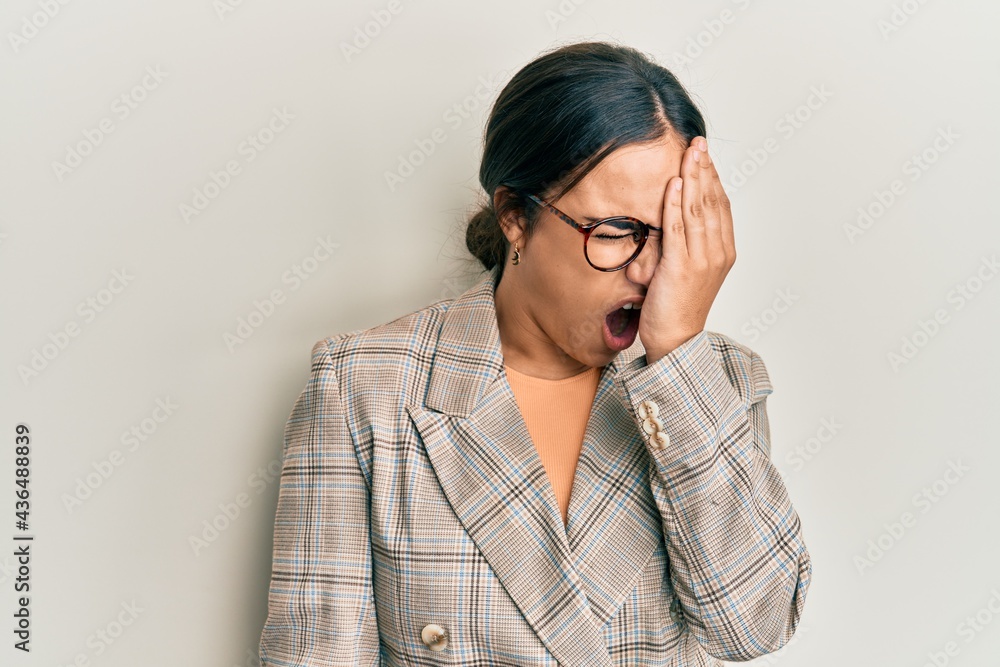 Young brunette woman wearing business jacket and glasses yawning tired covering half face, eye and mouth with hand. face hurts in pain. Young brunette woman wearing business jacket and glasses yawning tired covering half face, eye and mouth with hand. face hurts in pain.