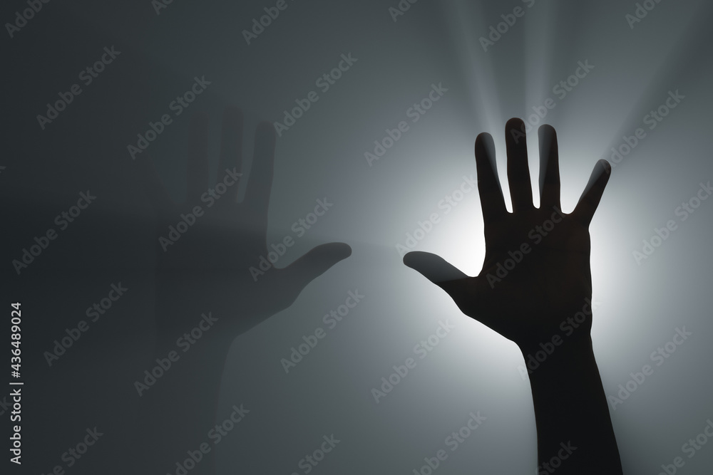 Silhouette of raised hands in the rays of the spotlight.