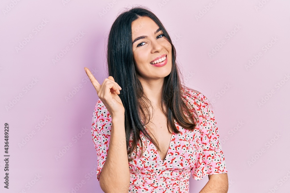 Young brunette woman wearing summer dress with a big smile on face, pointing with hand and finger to the side looking at the camera. Young brunette woman wearing summer dress with a big smile on face, pointing with hand and finger to the side looking at the camera.
