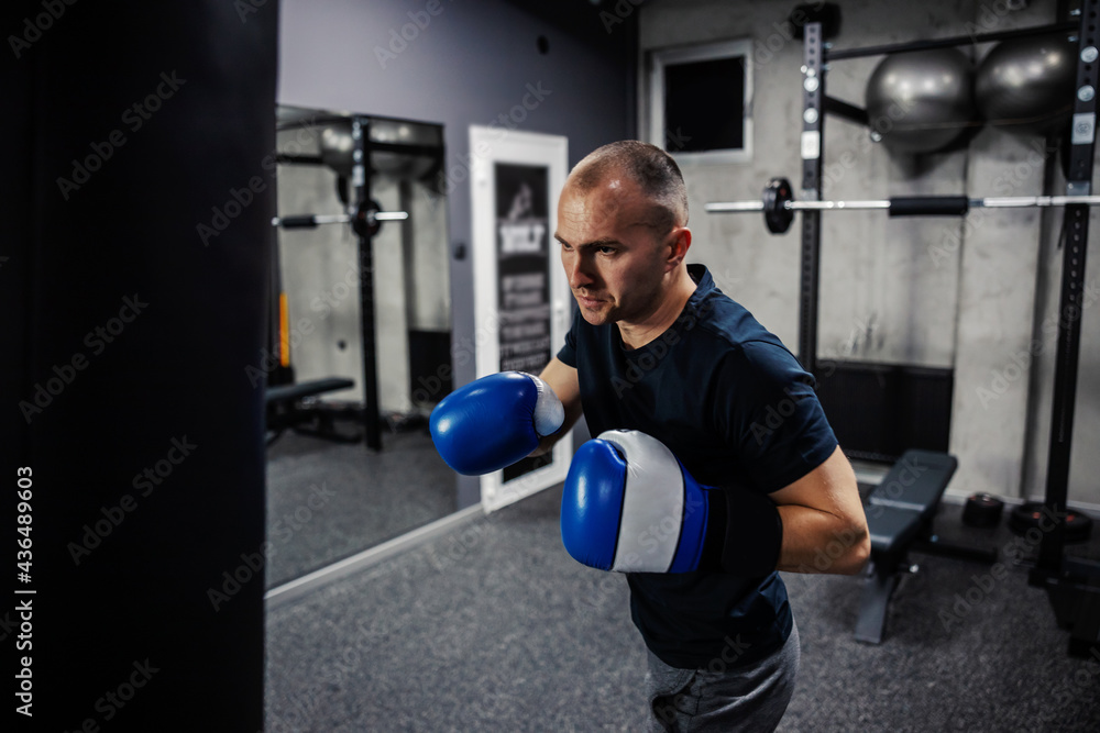 Kick boxing training. A dedicated man wears boxing gloves in an indoor