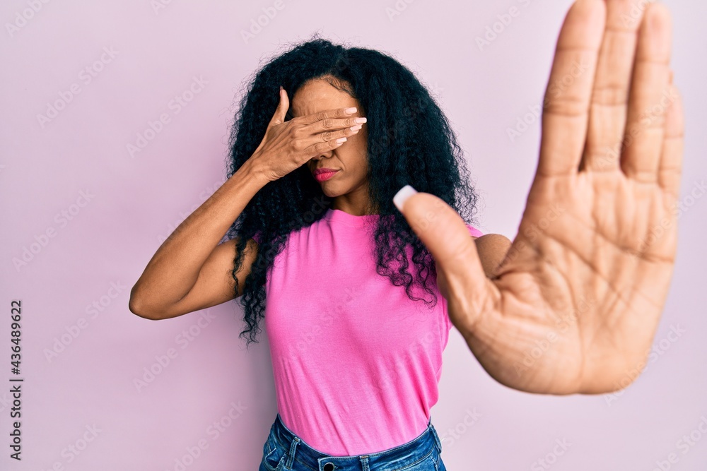 Middle age african american woman wearing casual clothes covering eyes with hands and doing stop gesture with sad and fear expression. embarrassed and negative concept. Middle age african american woman wearing casual clothes covering eyes with hands and doing stop gesture with sad and fear expression. embarrassed and negative concept.