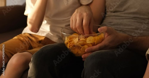 Men's and children's hands take chips from a bowl